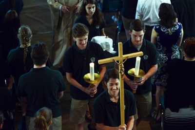 Students carry cross and candles at Mass.jpg